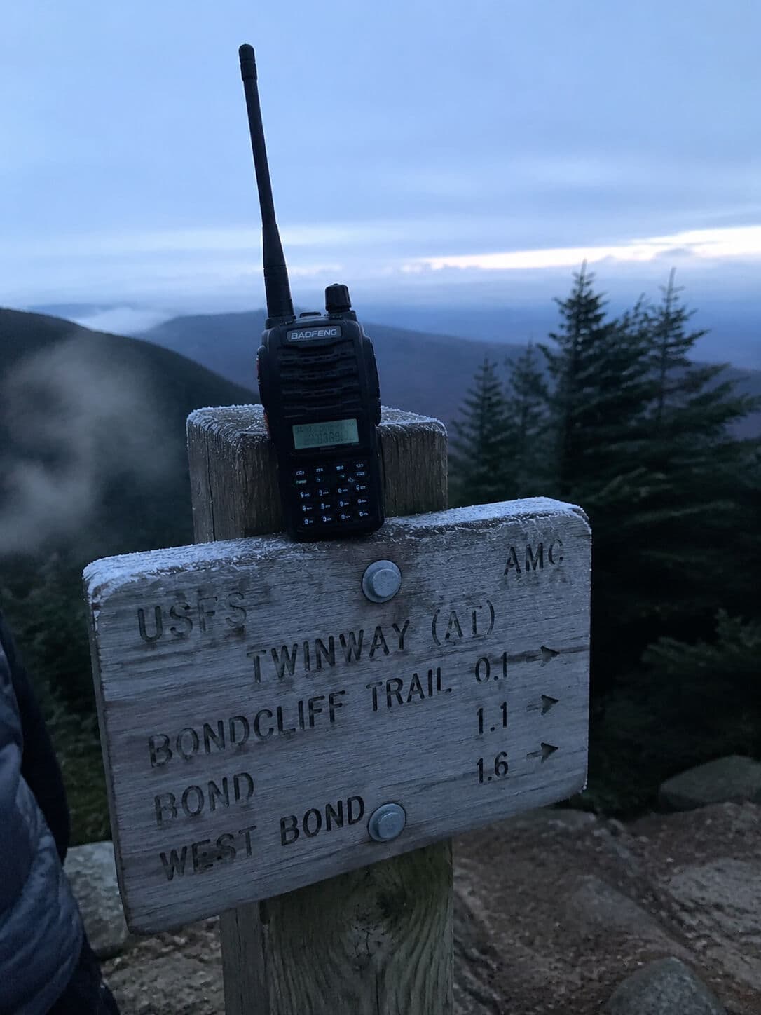 Baofeng UV-5R on a wooden post at a summit trail sign