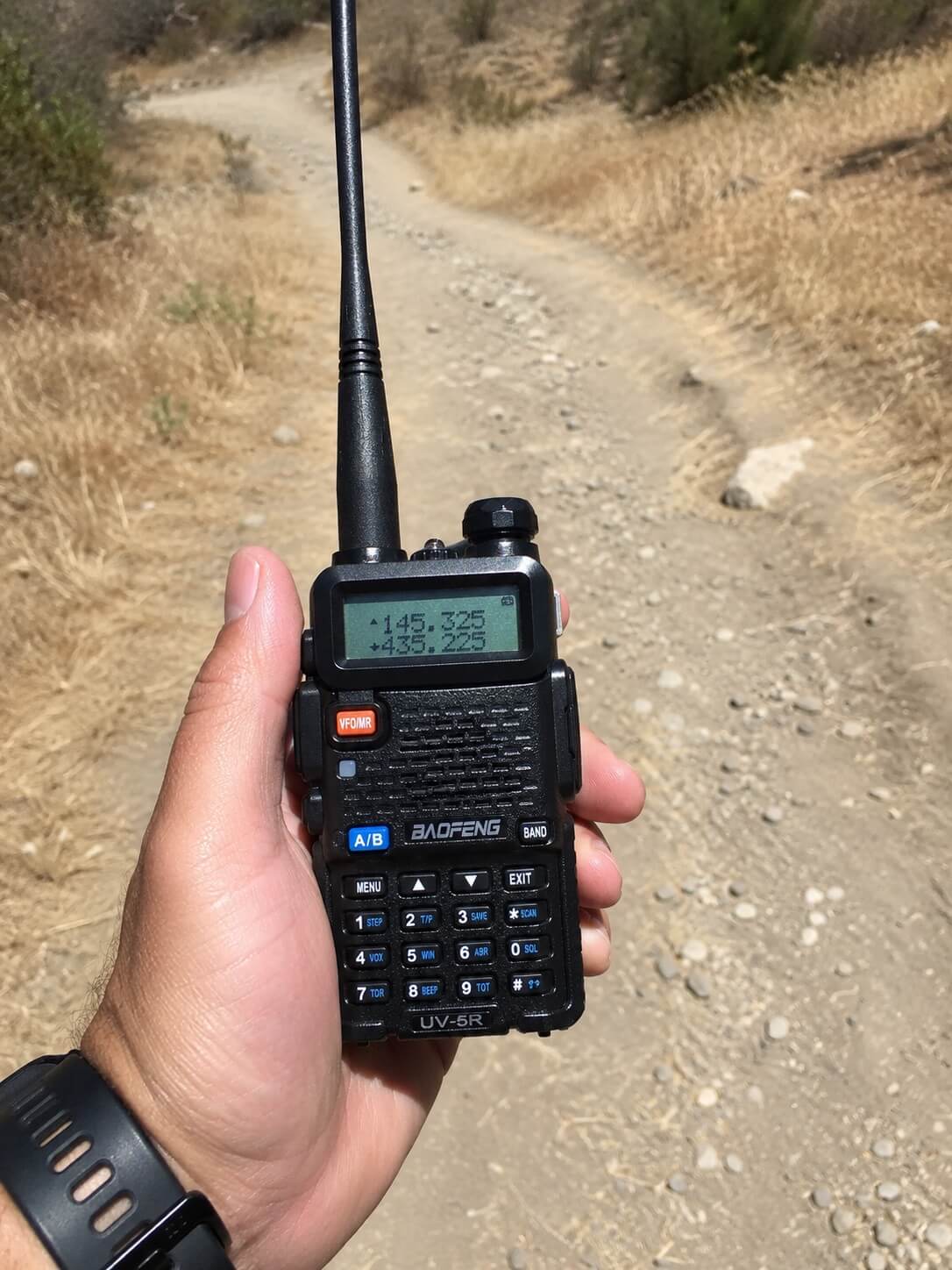 Operator holding a Baofeng UV-5R on a hiking trail